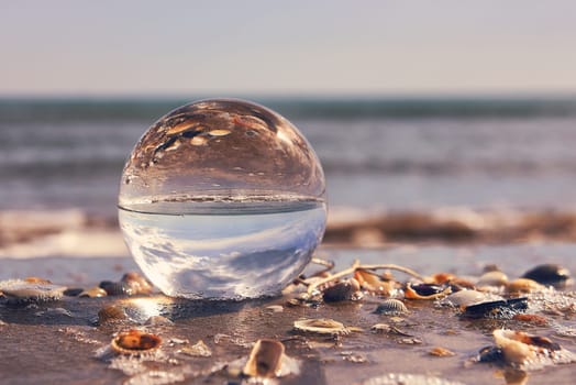 A beach landscape on a crystal ball. Photography techniques, sun, water, reflections, seashells, water, sun sun clear sky