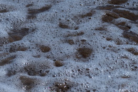 Detailed shot capturing foam from a breaking wave on sandy shore