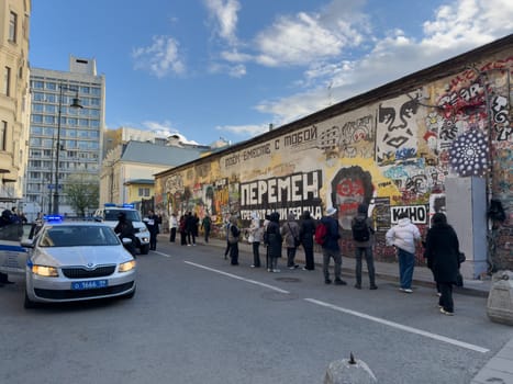 Moscow, Russia, April 26, 2025: People gather near the Viktor Tsoi wall on Arbat Street. Famous graffiti tribute to the legendary Soviet rock musician and leader of the band Kino