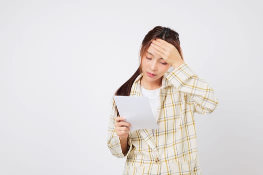 Financial stress overwhelms the Asian woman as she holds a bill in each hand, reviewing her financial troubles and unpaid bill stack with a worried face. isolated studio white background