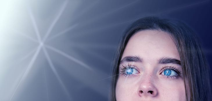 A young person with striking blue eyes looks up thoughtfully, illuminated by a gentle light that creates an ethereal atmosphere.