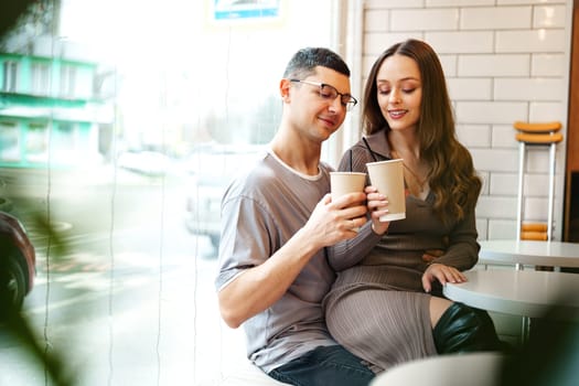 A young couple sits close together in a trendy cafe, smiling as they clink their coffee cups. The sunlight illuminates their relaxed atmosphere, enhancing their joyful connection.