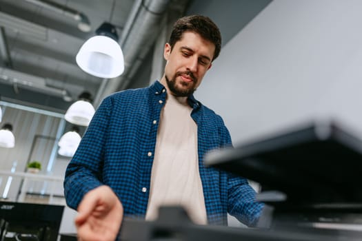 A man is focused on using advanced equipment in a stylish office space. The setting features modern decor, overhead lighting, and a professional atmosphere as he engages with his tasks.