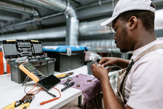 A technician works meticulously on equipment repairs in a well-lit workshop, surrounded by various tools. The activity highlights skills in a hands-on environment.