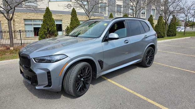 Ottawa, ON Canada - 04.22.2023: Sleek Gray Modern BMW X5 SUV Parked on Asphalt with Building Backdrop. Automotive Excellence