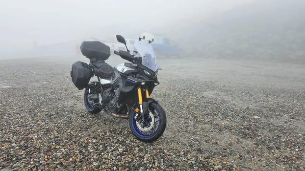 Sargents Purchase, NH USA - 08.22.2024: Motorcycle Adventure on a Foggy Day at Mountain Washington. Touring Bike Parked on a Gravel Road. Scenic Landscape