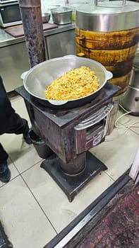 Bishkek, Kyrgyzstan - 10.05.2024: Hearty Asian Pilaf Simmering in a Traditional Cauldron on a Wood-Fired Stove.