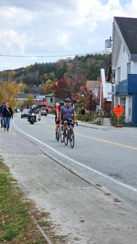 Gatineau, QC Canada - 10.20.2024: Cyclists ride along a scenic road in a charming town, enjoying the autumn landscape.