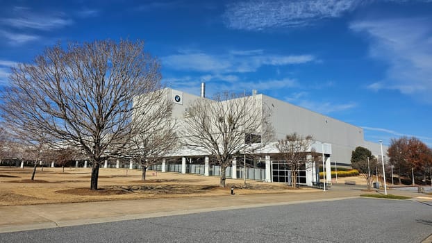 Greer, SC USA - 12.25.2024: Large Industrial Facility Exterior Under a Vibrant Blue Sky with Bare Trees Landscape.