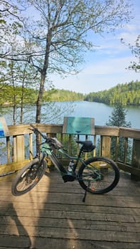 Gatineau, QC Canada - 05.13.2025: Electric Bicycle on Lakeside Deck with Scenic View, Serene Outdoor Adventure Awaits You.