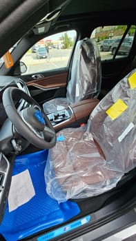 Ottawa, ON Canada - 09.12.2024: New Car Interior with Protective Covers, Modern Design, and Luxurious Brown Leather Seats.