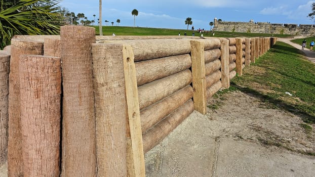 St. Augustine, FL USA - 12.24.2023: Rustic Log Retaining Wall Adds Natural Beauty to a Green Landscape on a Sunny Day Outdoors.