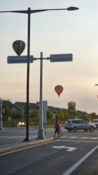Gatineau, QC Canada - 08.29.2024: Scenic Urban Intersection with Hot Air Balloons at Sunset People, Car, and Cityscape.