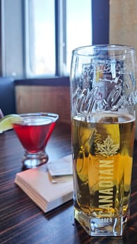 Brockville, ON Canada - 01.28.2025: Chilled Drinks on a Wooden Table Beer and Cocktail in a Refreshing Bar Setting.