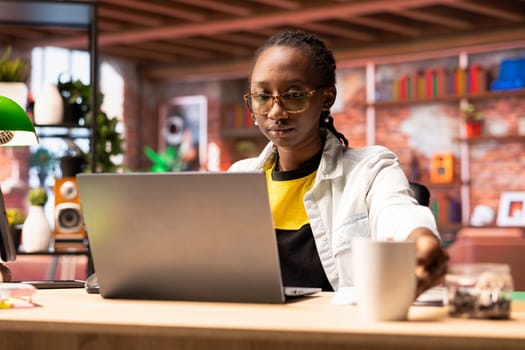 Teleworker using laptop device in apartment office to write emails. Remote employee in home workspace typing on notebook keyboard, composing documents in order to deliver project