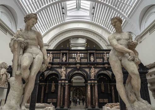 London, UK - May 07, 2025 - 16th century marble sculptures of Apollo and Zephyr by Francavilla with The pulpitum from St. John's Cathedral (s-Hertogenbosch) in the background, displayed inside Exhibition hall of The Victoria and Albert Museum in London, use it as your Wallpaper, Poster and Space for text, Selective focus.