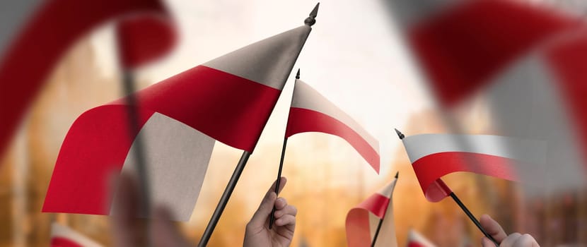 Poland flags in their hands on a blurred urban background. The photo illustration was created without the use of artificial intelligence, only using Photoshop.