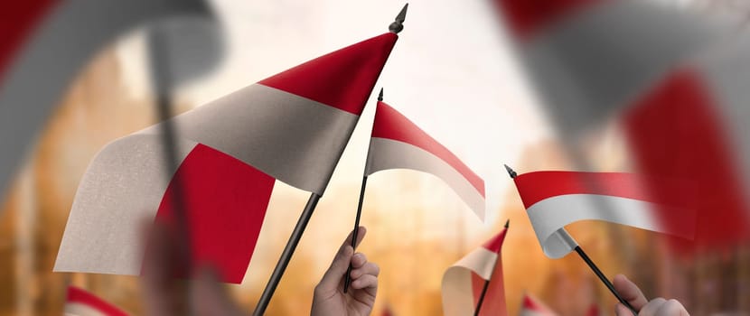 Indonesia flags in their hands on a blurred urban background. The photo illustration was created without the use of artificial intelligence, only using Photoshop.