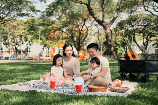 Happy Asian family enjoying a picnic in the park on a sunny day.