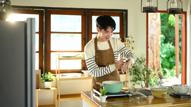 Asian man timing his cooking process with a smartwatch.