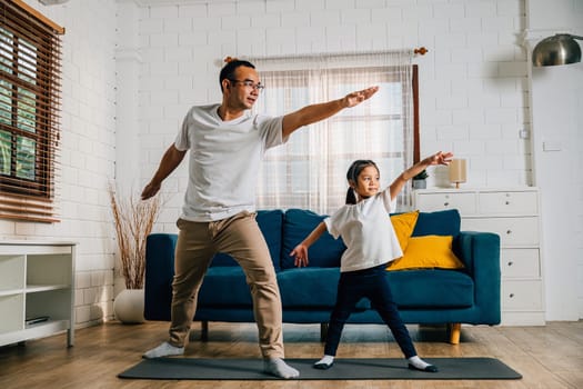 A father and his daughter bond through yoga in their living room fostering togetherness and happiness in their family fitness routine holding positions with smiles and care.