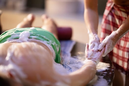 Hand Foam Therapy. Attendant gently washing patient hands with foamy soap in a traditional bath setting