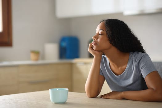 Black woman is relaxing sitting in a kitchen at home