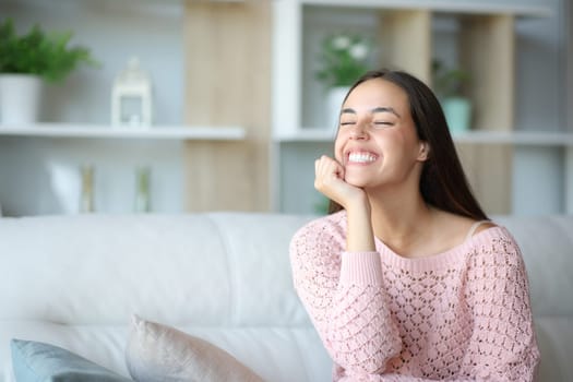 Happy woman sitting on a couch at home relaxing