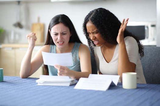 Angry women checking bank statement in the kitchen at home