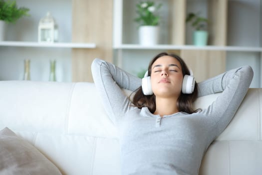 Woman relaxing with headphone listening audio sitting on a couch at home