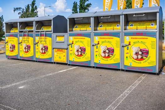 Hockenheim, Germany - 18 June 2023: New modern yellow collection bin for donating clothes and shoes to charity. Translation: join use, for environment