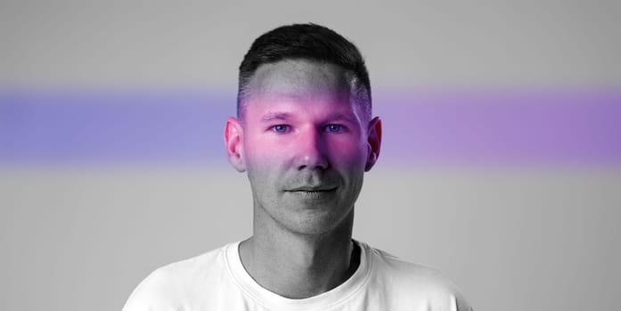 A man stands confidently in a creative studio environment, illuminated by vibrant light effects. His relaxed expression and unique backdrop emphasize modern artistic themes.