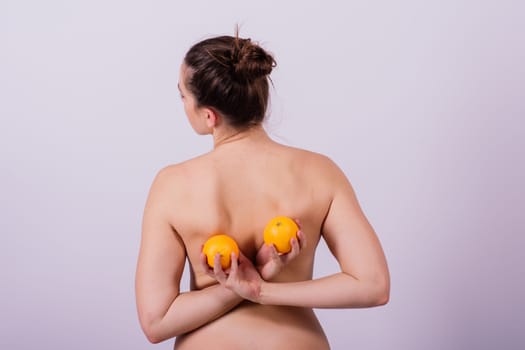 Naked woman back with an orange fruit an isolated image