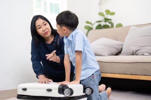 The mother engages her son in a conversation about their travel plans while they pack, creating a fun and educational experience about preparation for their trip.