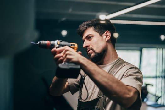 A man focuses intently while using an electric drill to work on a renovation project. Natural light illuminates the contemporary workspace, highlighting his concentration and craftsmanship.