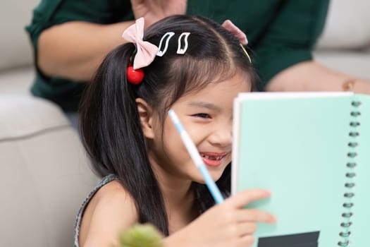 A young girl proudly holds up her drawing, smiling as her mother encourages her creativity. This moment reflects the joy of learning and anticipation for school.