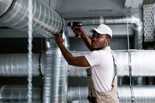 A technician works diligently on installing a ventilation duct in an industrial building. The focus is on precision and proper equipment usage, showcasing expertise in HVAC.