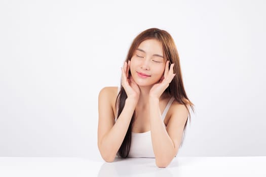Skin brightness and healthy skin are beautifully displayed as Asian woman gently touches her face, showing elegance, softness, calm satisfaction of complete skincare routine. isolated white background