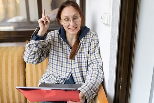 Businesswoman having a good idea while working from home, using laptop and holding a folder