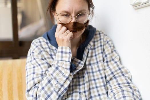 Woman with glasses making fake mustache with her hair while smelling it