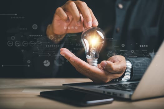 Businessman's hand holds a light bulb, representing the power of imagination. Highlights the concept of creativity, inspiration, and successful profit in global business.