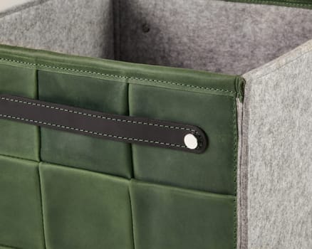 Close-up of a stylish green leather storage box featuring a gray felt lining and a sturdy leather handle