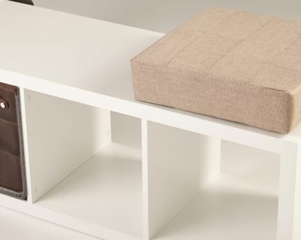 Stylish white storage bench featuring a comfortable beige cushion and empty compartments, perfect for organizing any living space