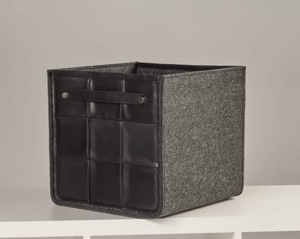 Modern gray felt storage box with black leather details, offering stylish organization