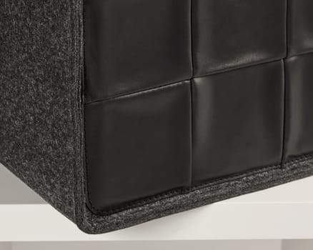 Close-up of a stylish black leather and felt storage box resting on a white shelf, showcasing its modern design and textured surfaces