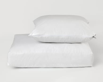 Clean white waterproof pillow and mattress protector on a white background, promoting hygiene and comfort