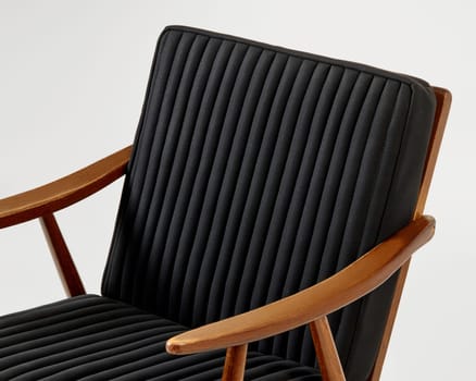 Comfortable black lounge chair with vertical channel tufting and light brown wooden frame, representing modern furniture design