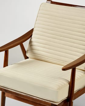 Wooden armchair with cream ribbed cushions offers a blend of comfort and style, perfect for adding a touch of elegance to any interior