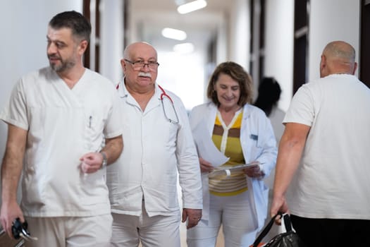 A group of healthcare professionals in white uniforms walking through a hospital hallway while reviewing patient documents and discussing treatment plans
