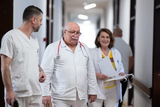 A group of healthcare professionals in white uniforms walking through a hospital hallway while reviewing patient documents and discussing treatment plans